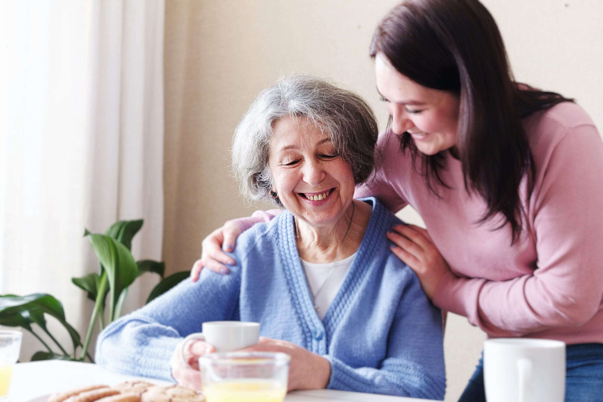 Resident of Valeo Memory Care - The Preserve Daughter and Mother smiling at breakfast table at the Preserve of Dunedin