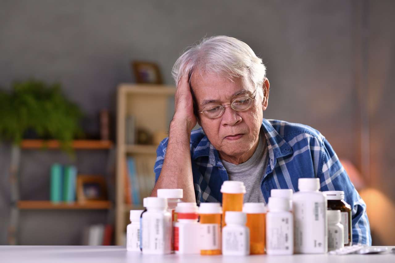 Older Adult Reviewing Medications at The Preserve at Dunedin - The Preserve A senior resident reviewing multiple medication bottles at The Preserve at Dunedin, an ECC-licensed community.