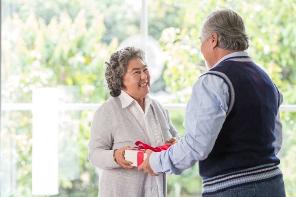 Gifting Joy to Residents at The Preserve - The Preserve A senior resident at The Preserve at Dunedin receiving a thoughtful Christmas present with a red bow on top